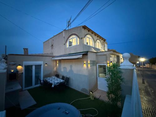 una piccola casa bianca con una panchina nel cortile di Villa para 12 personas en Santa Pola, frente a isla Tabarca a Gran Alacant