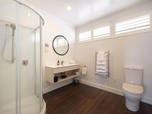 a bathroom with a toilet and a sink and a mirror at Suncourt Hotel & Conference Centre in Taupo