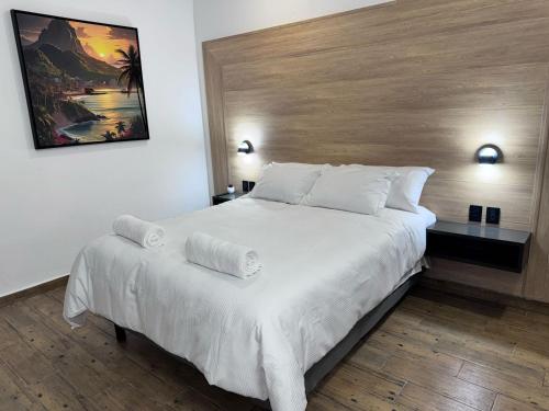 a bedroom with a large white bed with a wooden headboard at Casa ZeRo in Manzanillo