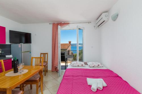 una stanza con un tavolo da pranzo e un letto con una coperta rosa di Apartments by the sea Lokva Rogoznica, Omis - 24321 a Lokva Rogoznica