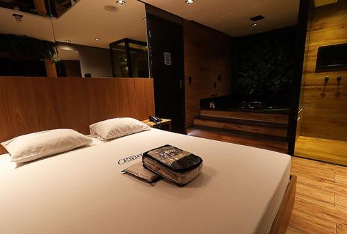 a bed with a suitcase sitting on top of it at Motel Riviera in Araraquara
