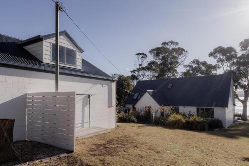 a white house with a black roof at Cliff-Top Retreat Ocean Views in Spring Beach