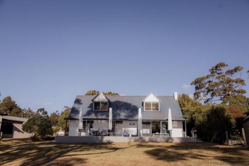 a large white house sitting on top of a yard at Cliff-Top Retreat Ocean Views in Spring Beach