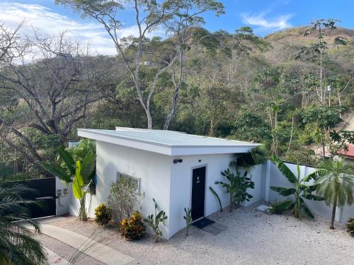 a white house with a mountain in the background at CASITA COCO in Playa Grande