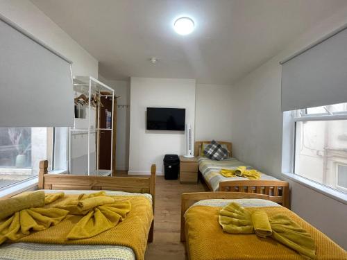 a room with two beds and a tv on the wall at Ariana House Hotel-Families and Couples Only in Blackpool