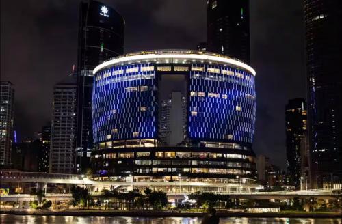 a large building with blue lights on it at night at Luxury apartment at Queens Wharf Tower in Brisbane