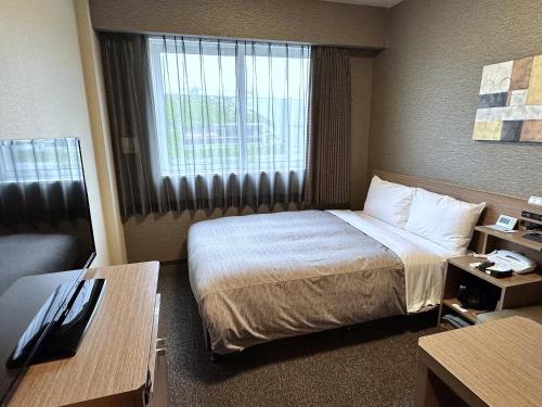 a hotel room with a bed and a window at Hotel Route-Inn Katori Sawara Ekimae in Katori