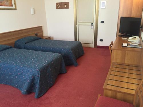 a hotel room with two beds and a desk at Hotel Arcobaleno in Vimodrone