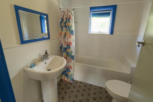 Un baño con lavabo, bañera e inodoro. en Classic Kiwi Bach Southbay, en Kaikoura