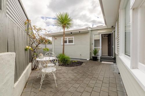 a patio with a table and a chair in front of a house at Webber by the Sea in Paraparaumu Beach