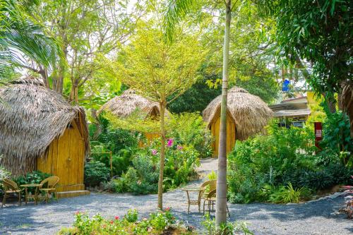a garden with tables and chairs and a hut at Samui Circus Studio and Ville - Hut Bungalow 1 in Amphoe Koh Samui