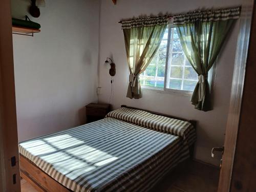 a small bedroom with a bed and a window at Cabañas El Duende in Quines