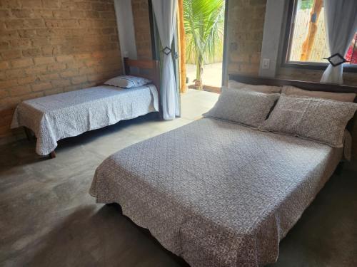 a bedroom with two beds and a window at Chalés Mirante da Lua Chalé 3 in Cavalcante