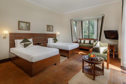 a hotel room with two beds and a couch at Gokarna Forest Resort Kathmandu in Kathmandu
