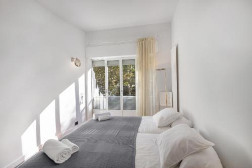 Un dormitorio blanco con una cama y una ventana. en Villa Cela, en Masnou