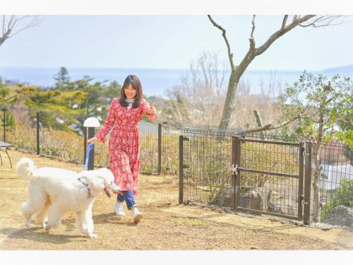 a woman walking a white dog near a fence at LiVEMAX Resort Izu Kogen Terrace & Spa in Ito