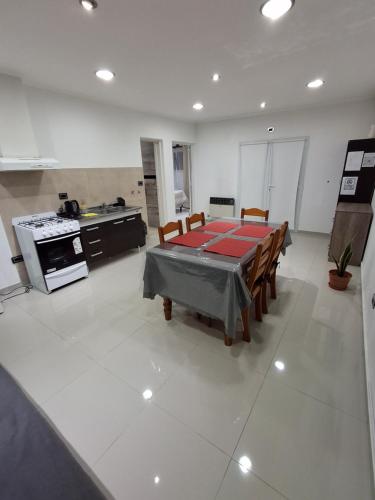 a living room with a table and a kitchen at Alojamiento ByB in Plottier