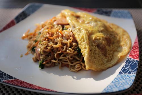 a plate of food with a sandwich and noodles at Dewi Villa Padangbai Hotel in Padangbai