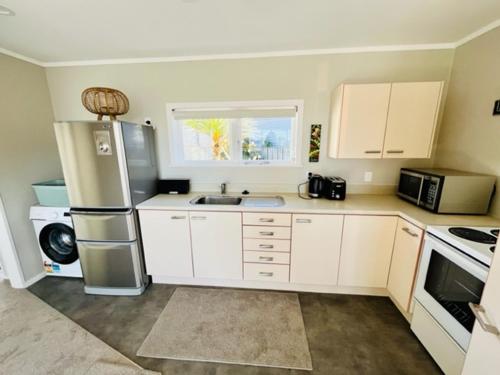 a small kitchen with white cabinets and a sink at Webber by the Sea in Paraparaumu Beach