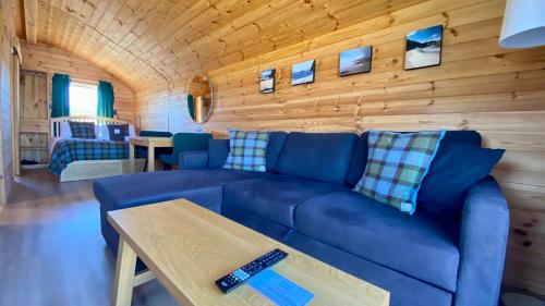 a living room with a blue couch and a wooden wall at SEApods - Isle of Lewis - Luxury en-suite pods on the edge of the Atlantic Ocean in Aird Uig