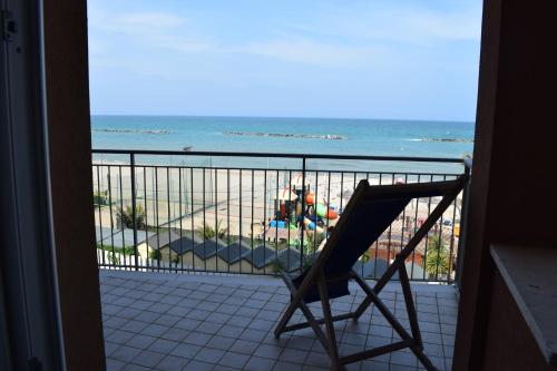 a chair on a balcony with a view of the beach at Hotel Astoria in Pesaro