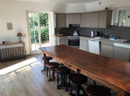 a kitchen with a large wooden table and stools at Petite maison joyau avec vue imprenable sur Canne in Mougins