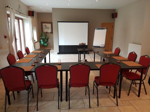 Una sala de conferencias con mesas, sillas y una pantalla. en B&B Espace Tello, en Jodoigne