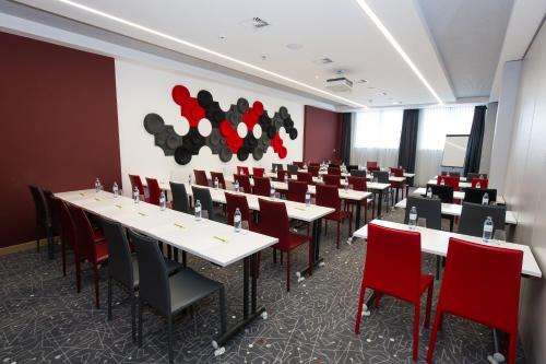 a conference room with tables and red chairs at AIGO Welcome Family Resort in Aigen im Mühlkreis