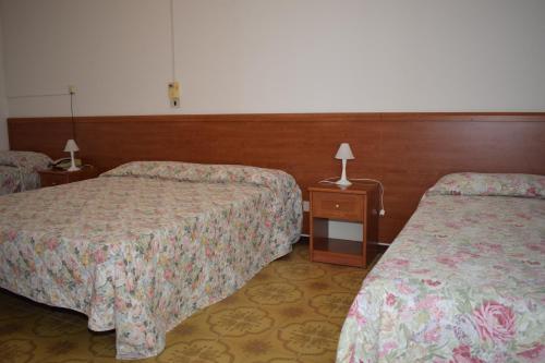 a hotel room with two beds and a table with lamps at Hotel Astoria in Pesaro