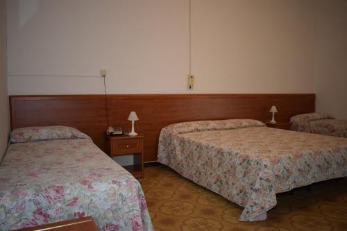 a hotel room with two beds and two lamps at Hotel Astoria in Pesaro