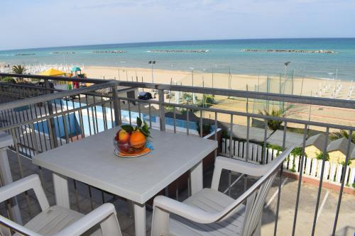 a table with a bowl of fruit on a balcony with the beach at Hotel Astoria in Pesaro