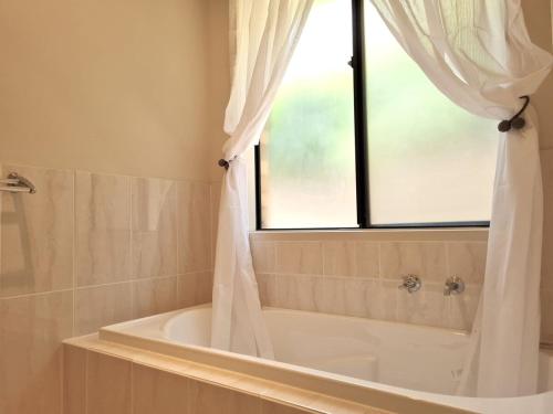 a bathroom with a bath tub and a window at Moonta Bay Getaway in Port Moonta