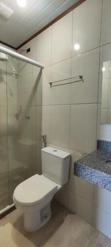 a bathroom with a toilet and a glass shower at Pousada Gabriel in Praia de Araçatiba