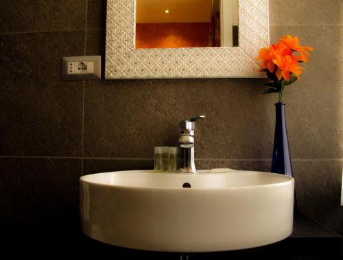 a white sink in a bathroom with a vase with orange flowers at Roma Veneto Relais in Rome