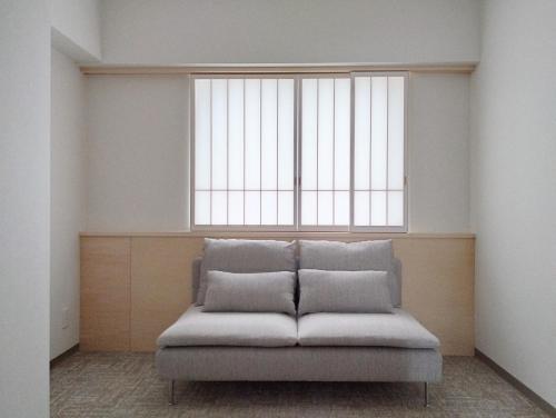 吹田市にあるApartment Hotel DIG the OSAKAの大きな窓のある客室で、ソファが備わります。
