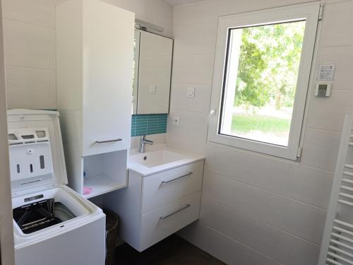 Elle comprend une petite cuisine blanche avec un évier et une fenêtre. dans l'établissement Charmante Longère Bretonne au Calme, Proche Mer - FR-1-639-135, à Sarzeau