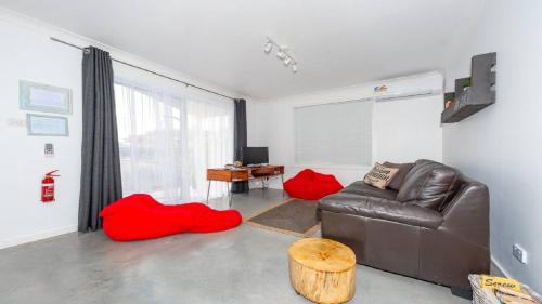 a living room with a leather couch and red pillows at Salty Kisses Holiday House in Point Clare