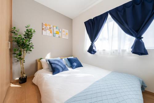 a bedroom with a bed with blue curtains and a window at 70sqm Private House, Major Tokyo Spots & Free Parking in Tokyo
