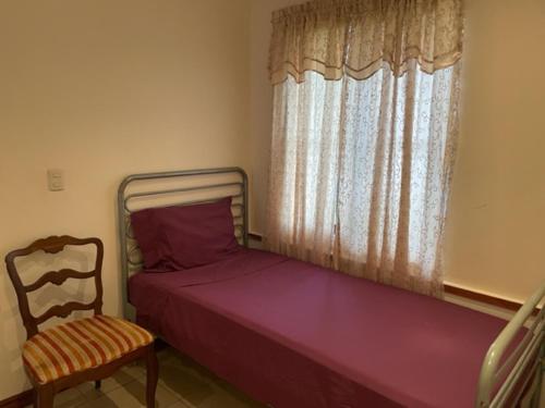 a bedroom with a bed and a chair and a window at House in paquera in Tapantí
