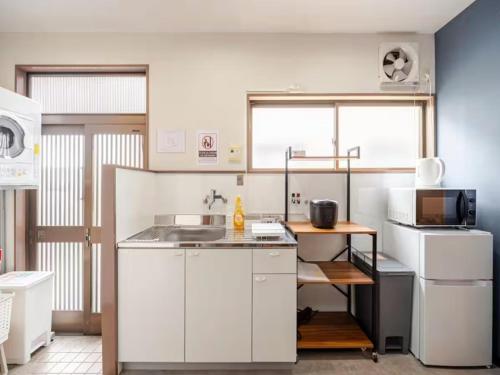 a small kitchen with white cabinets and a sink at 402 Newly opened Hotel Baika Family friendly Free parking 10 minutes to USJ in Osaka