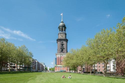 a building with a clock tower in the middle of a park at Appartements in der historischen Deichstrasse contactless Check in in Hamburg