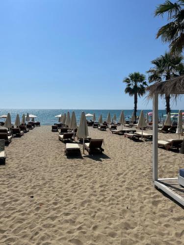 a row of beach chairs and umbrellas on a beach at Golem Beach Apartment - Very Large - Self Check In - Parking Available in Golem
