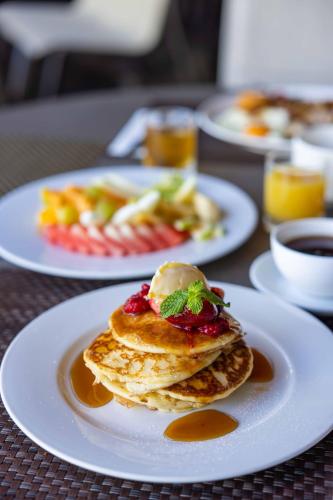 three plates of food on a table with pancakes at Chateau Royal Beach Resort & Spa, Noumea in Noumea