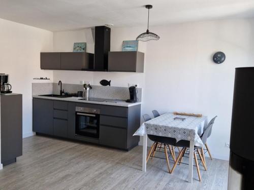 une cuisine avec un évier et une table avec des chaises dans l'établissement Maison à Barbâtre, proche plage, animaux admis - FR-1-823-37, à Barbâtre