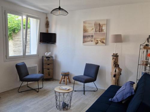 un salon avec un canapé bleu et deux chaises dans l'établissement Maison à Barbâtre, proche plage, animaux admis - FR-1-823-37, à Barbâtre