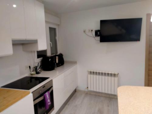 a kitchen with white cabinets and a television on the wall at Excelente ubicacion in Pamplona