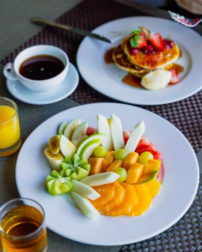 two plates of food with fruit on a table at Chateau Royal Beach Resort & Spa, Noumea in Noumea
