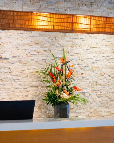 a vase with orange flowers sitting on a counter at Chateau Royal Beach Resort & Spa, Noumea in Noumea