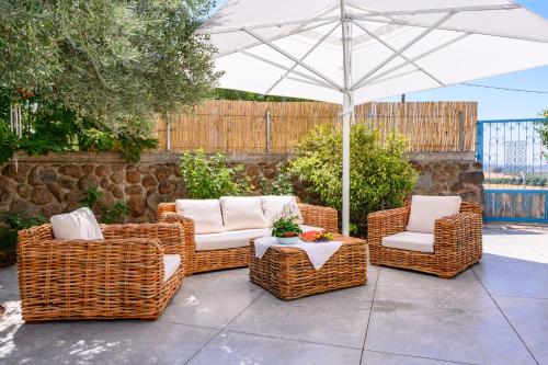 three wicker chairs and an umbrella on a patio at Ettys Villa in Giv'at Yo'av