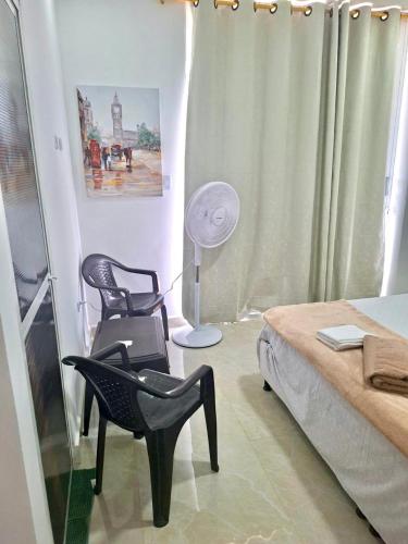 a bedroom with two chairs and a bed and a lamp at Perla del río habitaciones in Barranquilla